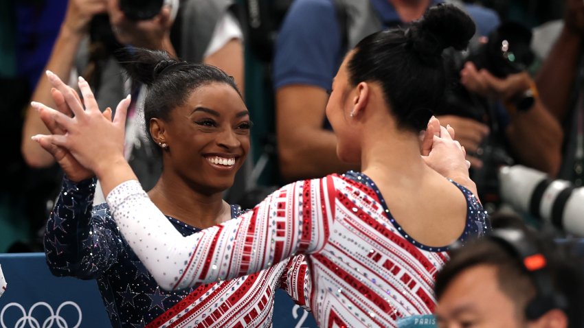 Sunisa Lee of Team United States reacts with teammate Simone Biles