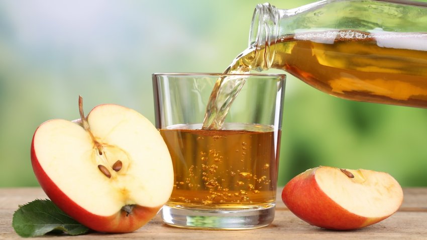 Apple juice pouring from red apples fruits in summer into a glass